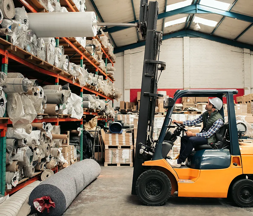 Worker pulling out a carpet roll with a fork lift in a flooring warehouse
